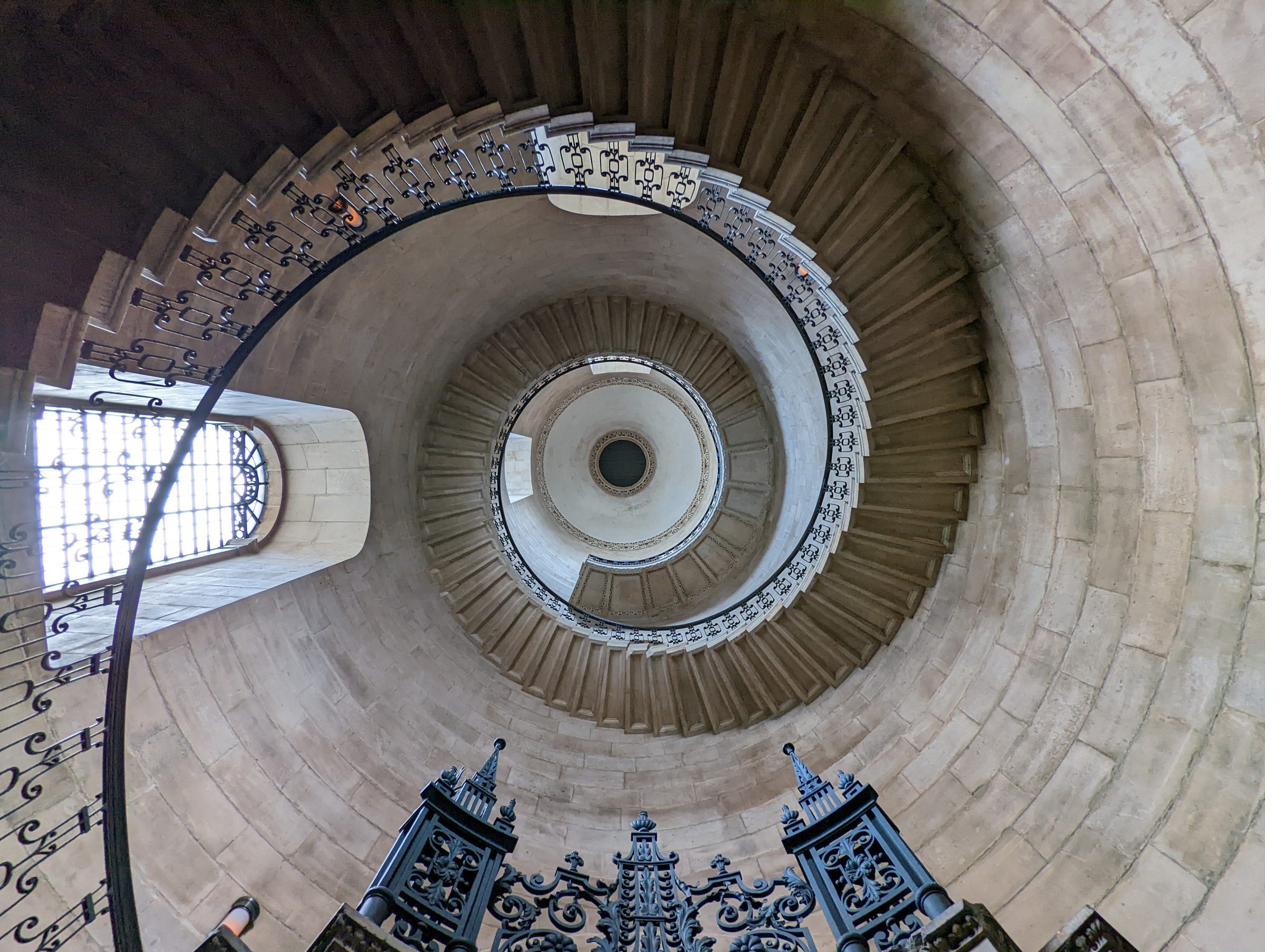 View up a helical stone staircase, showing the structural geometry of the stair and balustrade